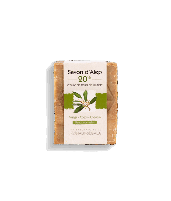 Une barre rectangulaire de Savon d'Alep 20% laurier du Laboratoire Haut-Ségala, enveloppée dans une bande de papier crème et verte. L'étiquette indique "Savon d'Alep", "20% d'huile de baies de Laurier", "Visage - Corps - Cheveux", "Peaux normales". C'est un savon d'Alep naturel pour une hygiène quotidienne bio.