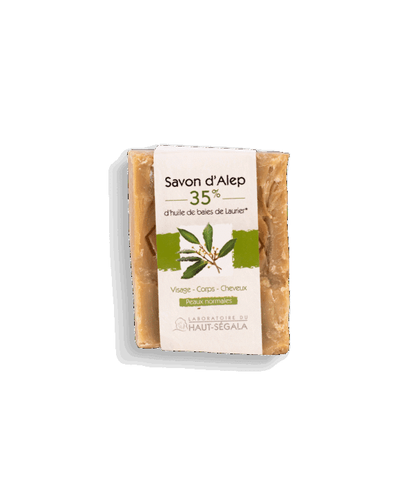 Une barre rectangulaire de Savon d'Alep 35% laurier du Laboratoire Haut-Ségala, enveloppée dans une bande de papier crème et verte. L'étiquette indique "Savon d'Alep", "35% d'huile de baies de Laurier", "Visage - Corps - Cheveux", "Peaux normales". C'est un savon d'Alep peaux normales pour un soin visage corps cheveux naturel.