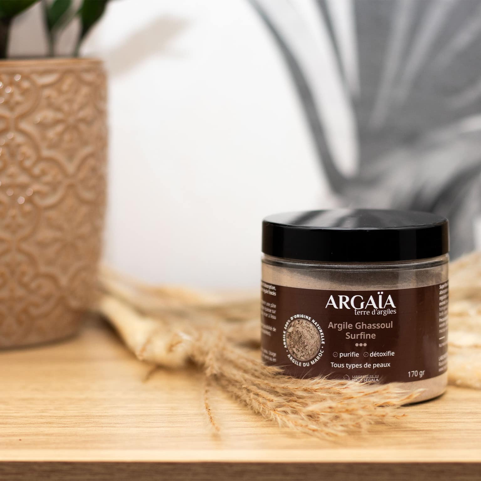 Pot d'Argile Ghassoul Surfine de la marque Argaïa, posé sur une surface en bois.