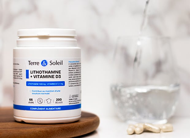 Flacon de complément alimentaire Lithothamne + Vitamine D3 biologique de la marque Terre & Soleil, avec un verre d'eau et des gélules.