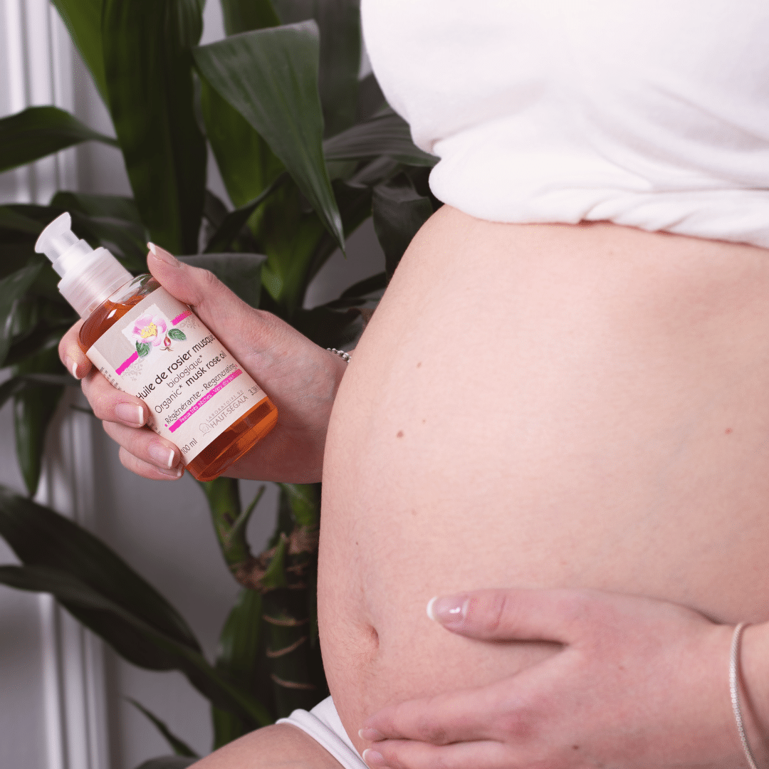 Une personne enceinte applique une huile de rose musquée sur son ventre.