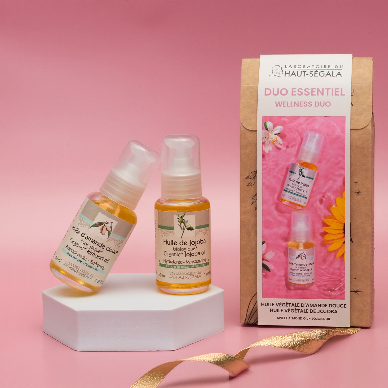 Main tenant un coffret "Duo Essentiel" du Laboratoire Haut-Ségala, contenant des flacons d'huile d'amande douce et d'huile de jojoba biologiques.