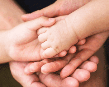 Les mains de trois personnes d'âges différents (un adulte, un enfant et un bébé) sont empilées, symbolisant le soin naturel famille et la transmission du bien-être toutes générations. L'image évoque la douceur et la protection de la peau avec des produits doux peaux sensibles et des cosmétiques bio enfants.